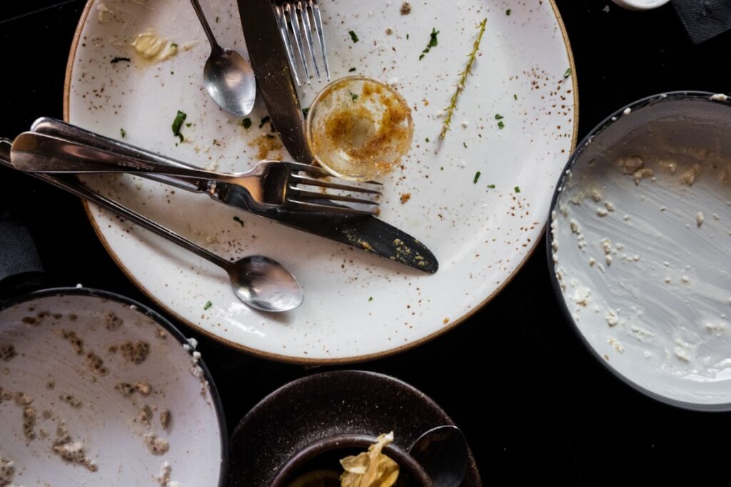 An overhead view of dirty plates scattered with utensils and food remnants after a meal.