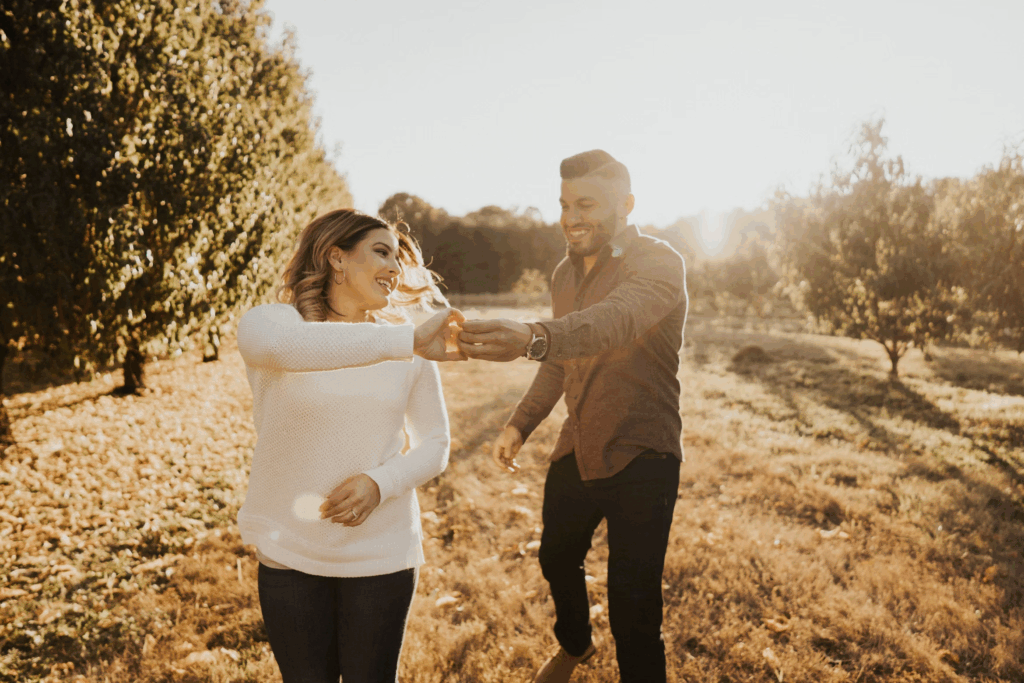 man and woman wearing sweaters in hay during sunset