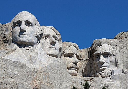 A picture of Mount Rushmore National Monument. Sculptures of George Washington, Thomas Jefferson, Theodore Roosevelt, and Abraham Lincoln.