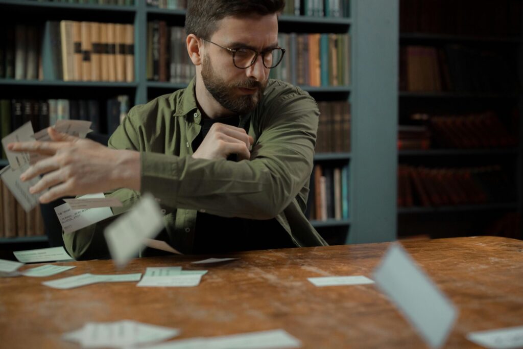 A Man in Glasses Throws Cards at a Library Desk