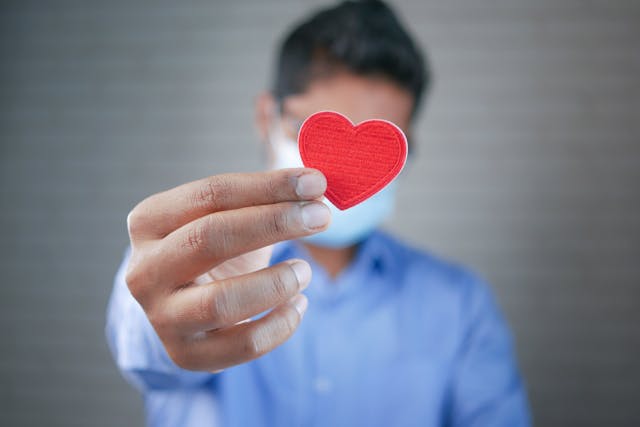 man holding a paper heart up towards the camera