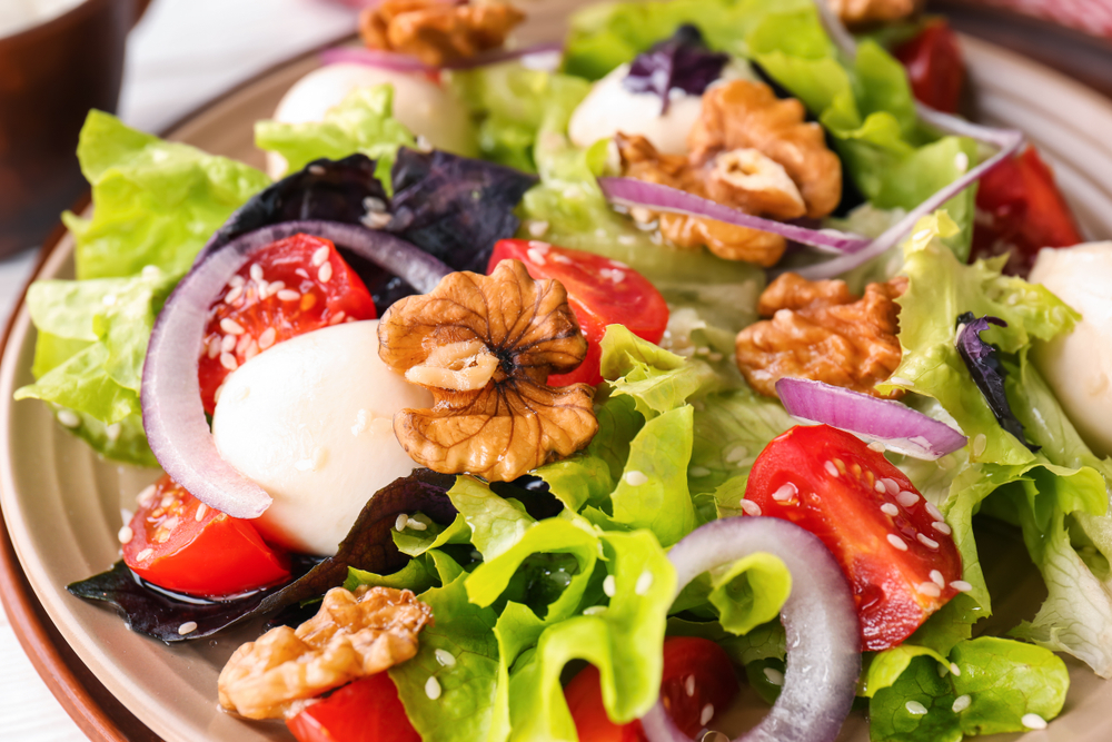 Delicious fresh salad with walnuts on a plate, close up