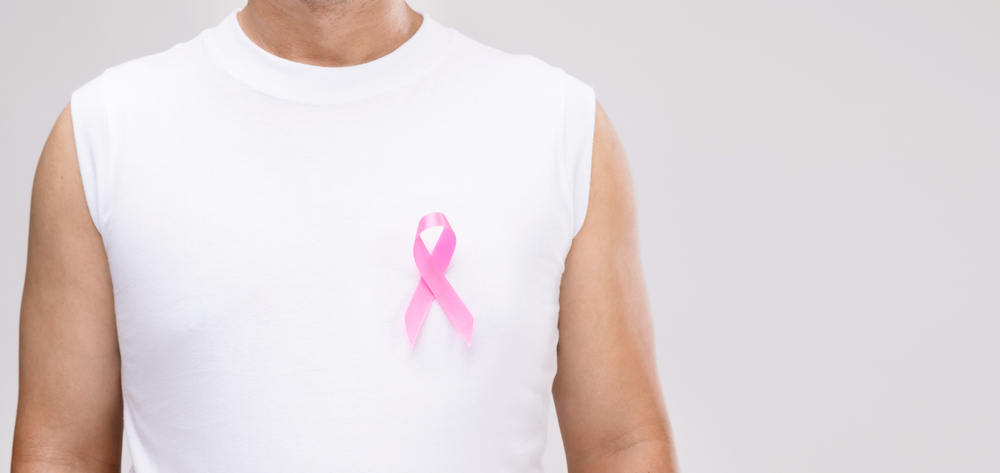 Male breast cancer concept : An image of an Asian man and a pink ribbon is a breast cancer campaign symbol. Studio shot isolated on gray background