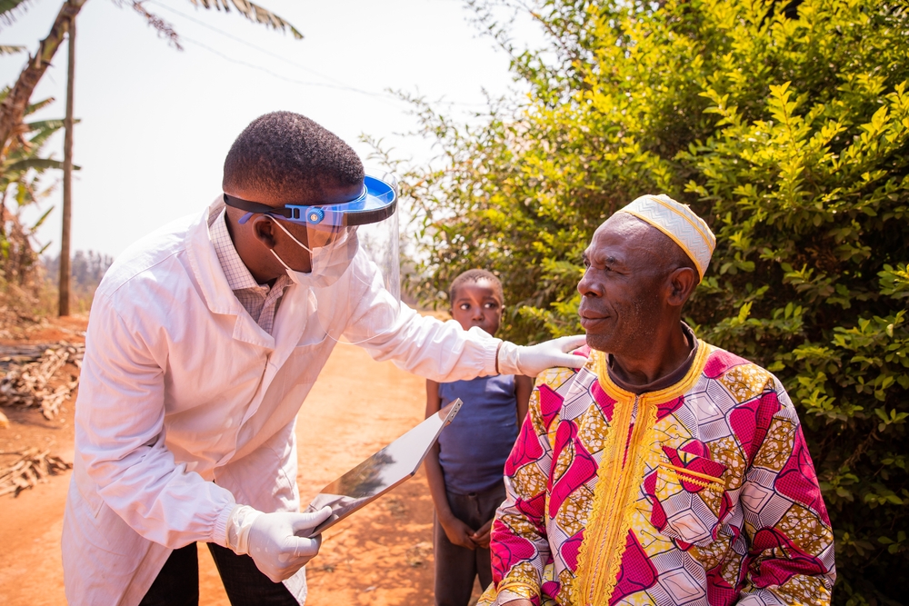 An African doctor visits an elderly patient and they talk during a medical examination. The concept of health care in Africa