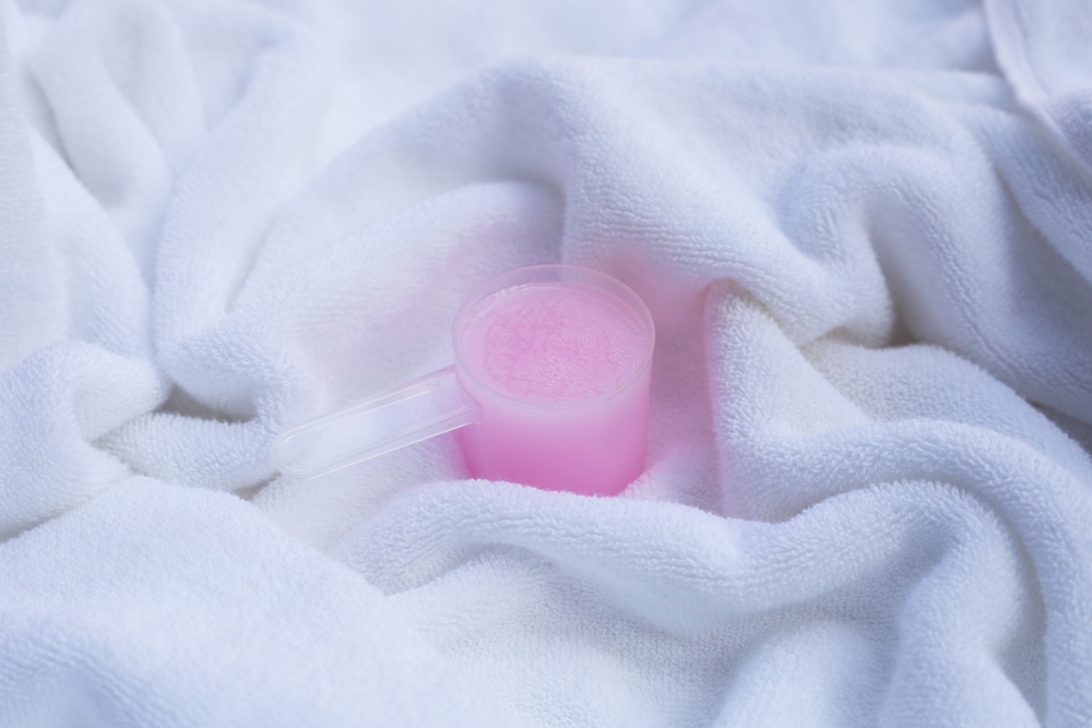 Fabric softener in a towel measuring spoon. The concept of washing.