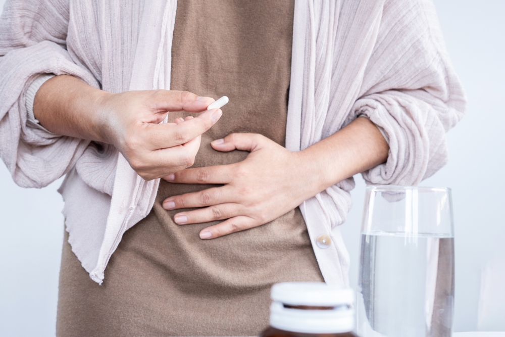 A woman with her hand taking a probiotic pill for the treatment of diarrhea