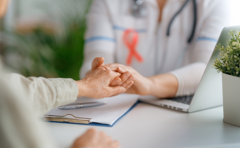 Pink ribbon for breast cancer awareness. Female patient listening to doctor in medical office. Support people living with tumor illness.