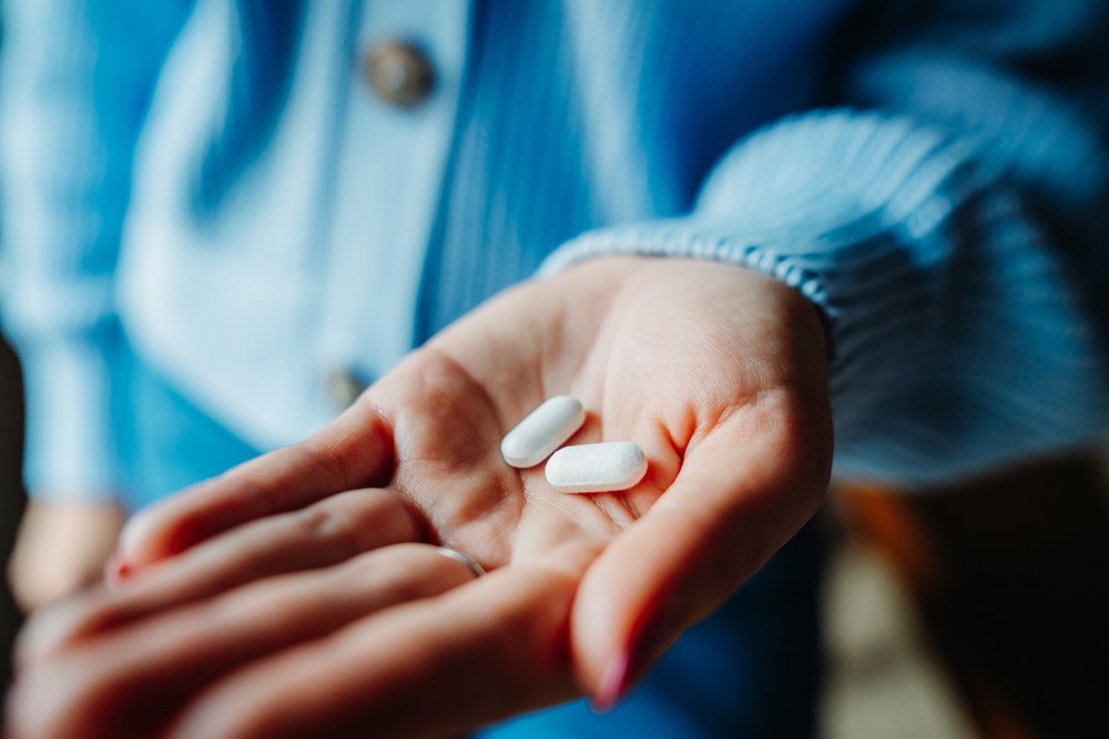 Close up of woman's hand holding two pills

