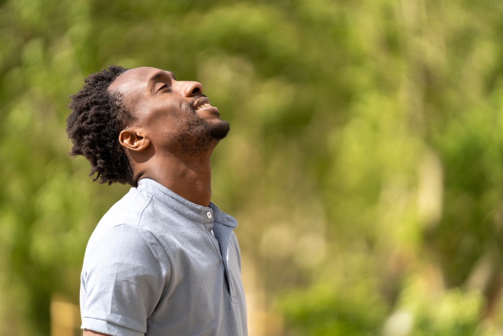The man looks skyward with a peaceful expression, basking in a moment of tranquility.