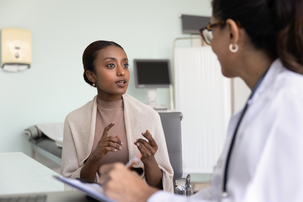 Young patient African woman consulting doctor in clinic, telling doctor about health care complaints by writing notes, talking to medical specialist, asking for treatment, prescription for pills