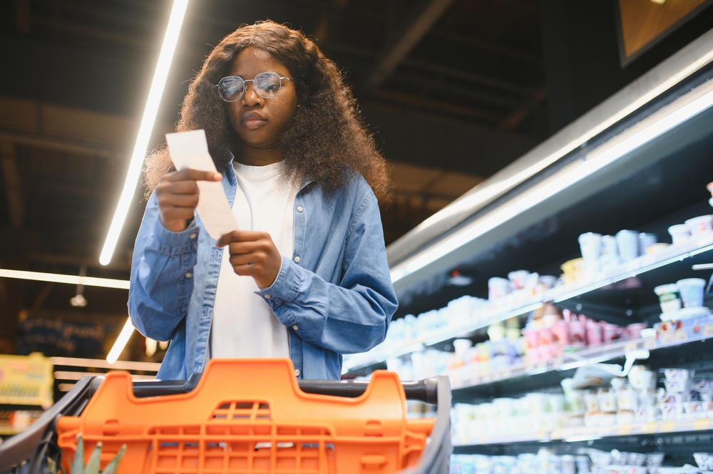 Shocked woman checking a long grocery receipt at the supermarket, expensive grocery and inflation concept.
