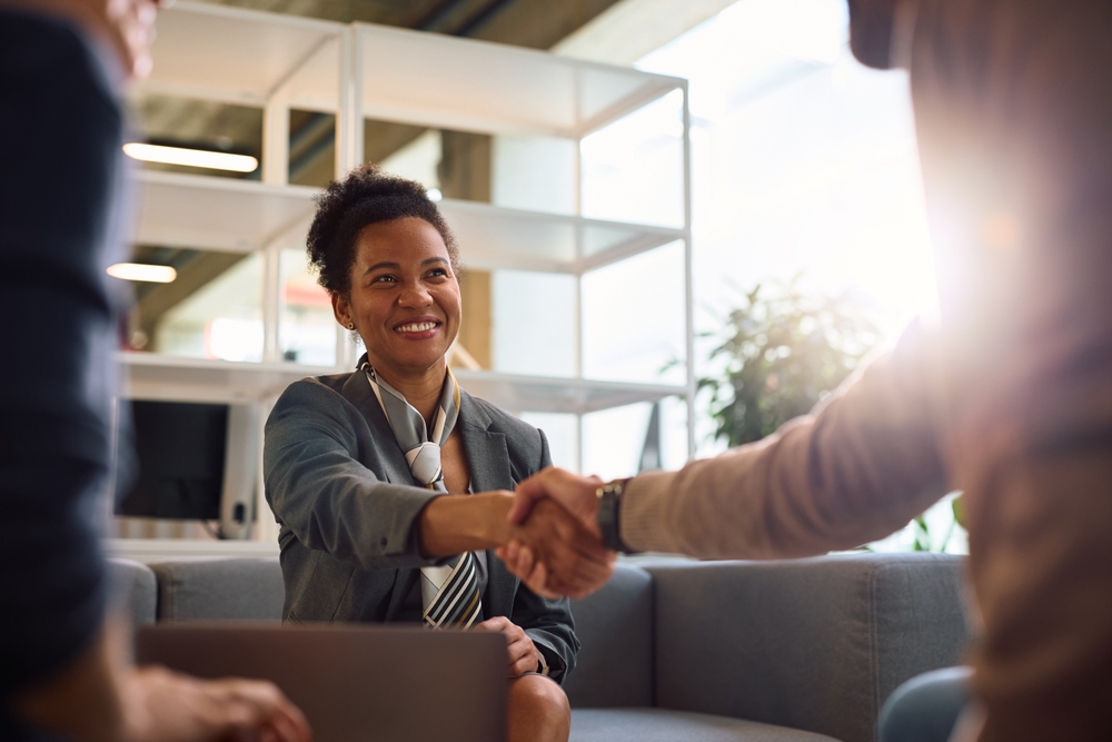 Happy black financial consultant shaking hands with her client in the office.