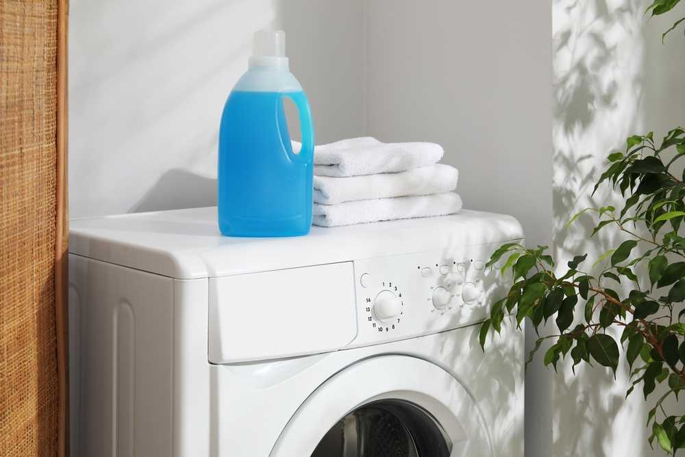 A bottle of fabric softener and towels in the washing machine in the house