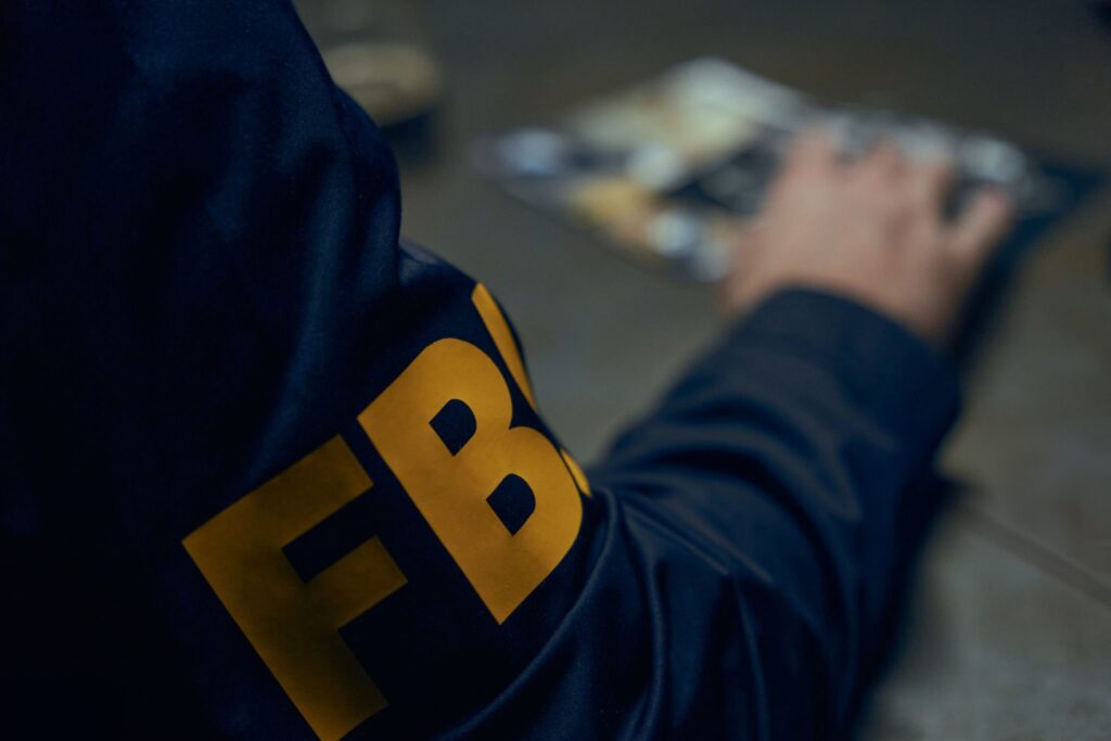 Close up on FBI sign on uniform of the agent, only an arm is in the frame. FBI in close-up
