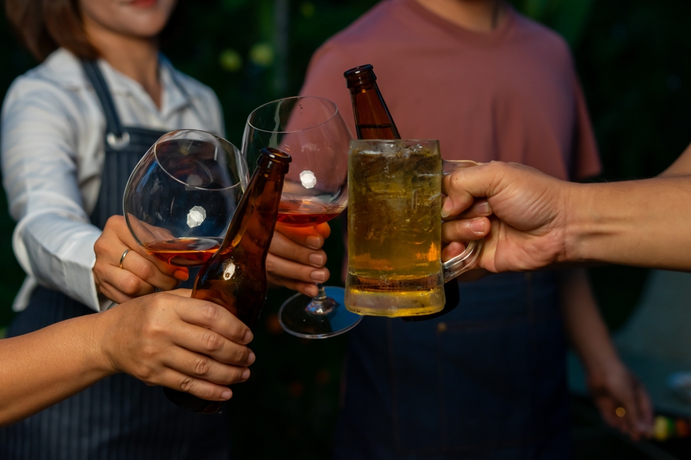 People are toasting beer bottles and wine glasses in an informal gathering
