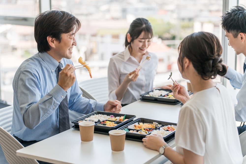 Men and women eat lunch, packed lunch, delivery lunch, or lunch in the company cafeteria (employee benefits)