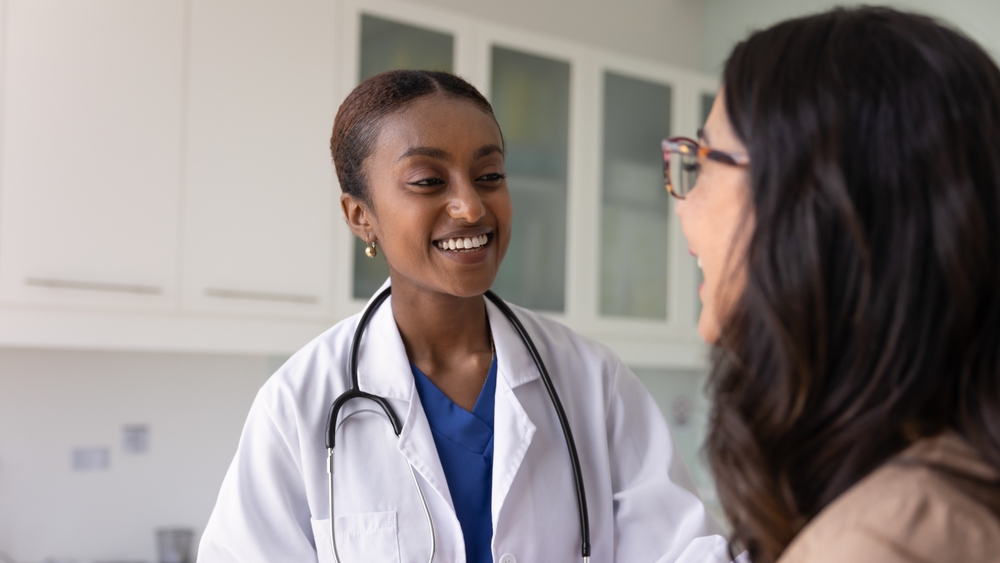 Close up of young African woman doctor talking with older patient, smiling, expressing friendly relation, provide professional medical care and lifestyle recommendation. Empathy, patient care, mission
