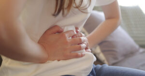 Study Finds the Most Intense Pain Humans Are Capable of Experiencing woman bracing her abdomen in pain