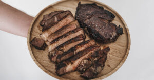 Round cutting board with sliced steak on it
