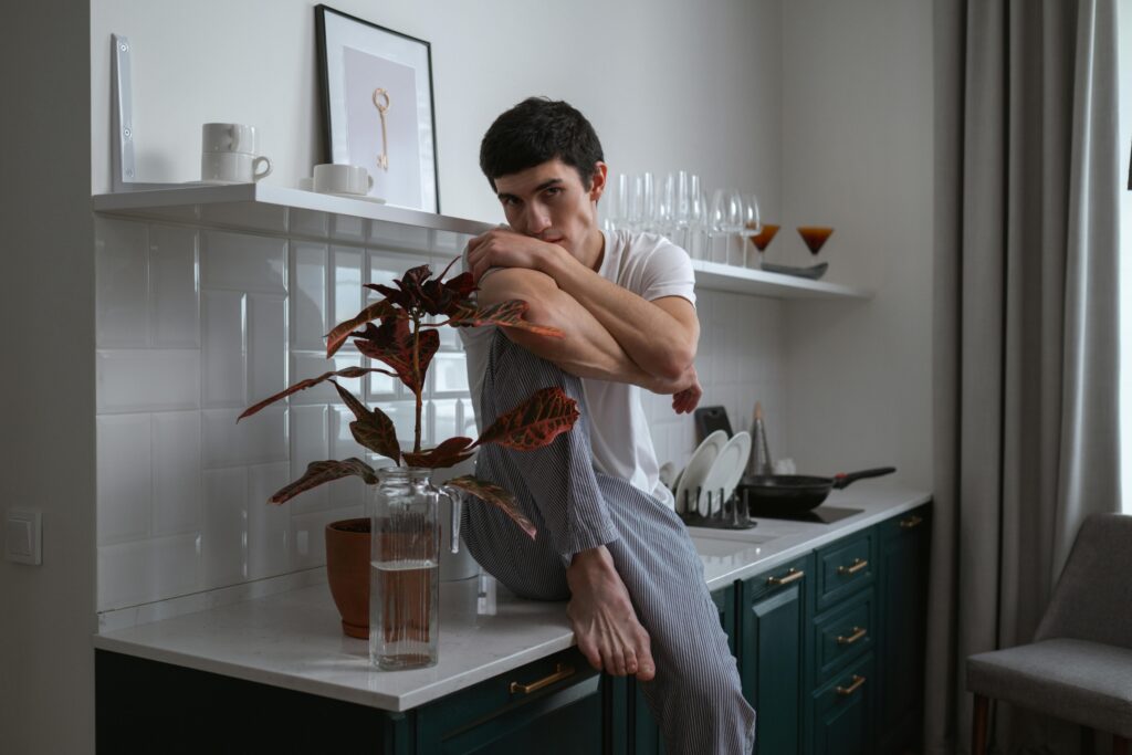 Man in White Crew Neck T-shirt Sitting on the Kitchen Counter
