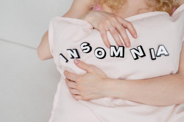 woman holding a pillow with insomnia written on it