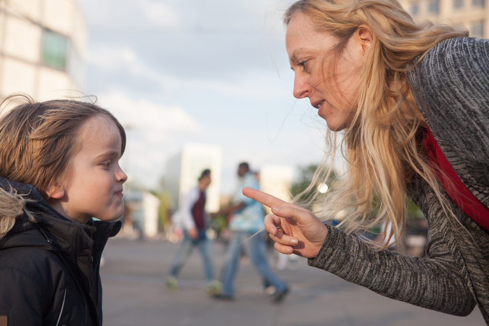 A mother, drawing attention, scolds her young son
