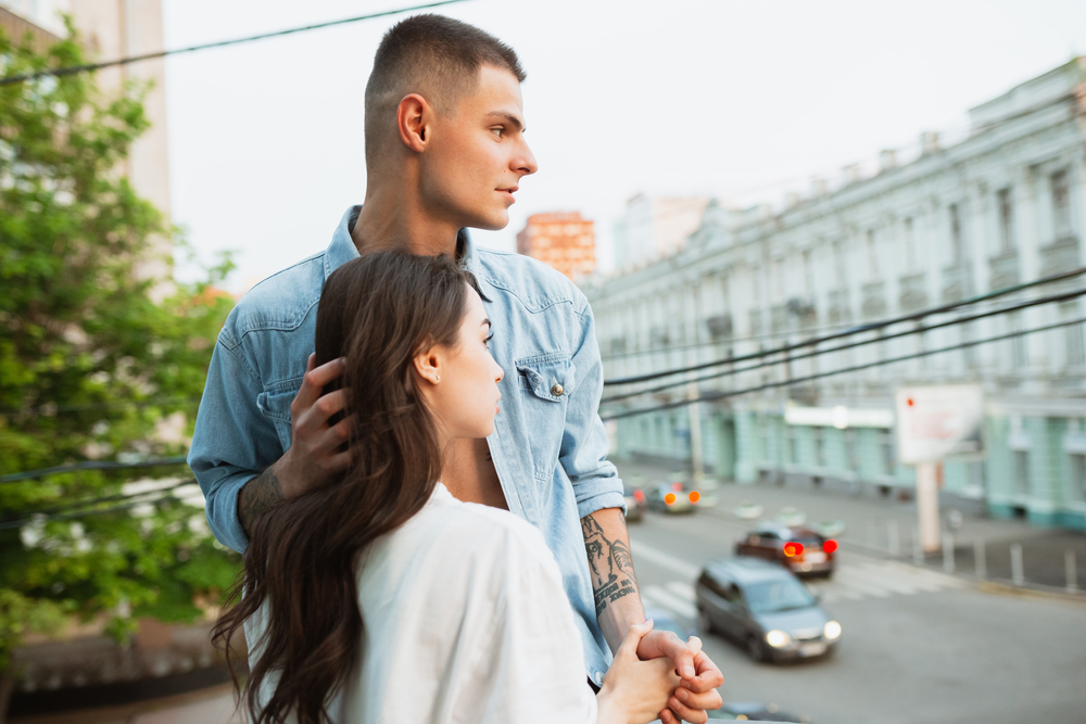 On the balcony, lovely. Quarantine lockdown, stay home concept - young beautiful caucasian couple enjoying new lifestyle during coronavirus health emergency. Happiness, togetherness, healthcare.
