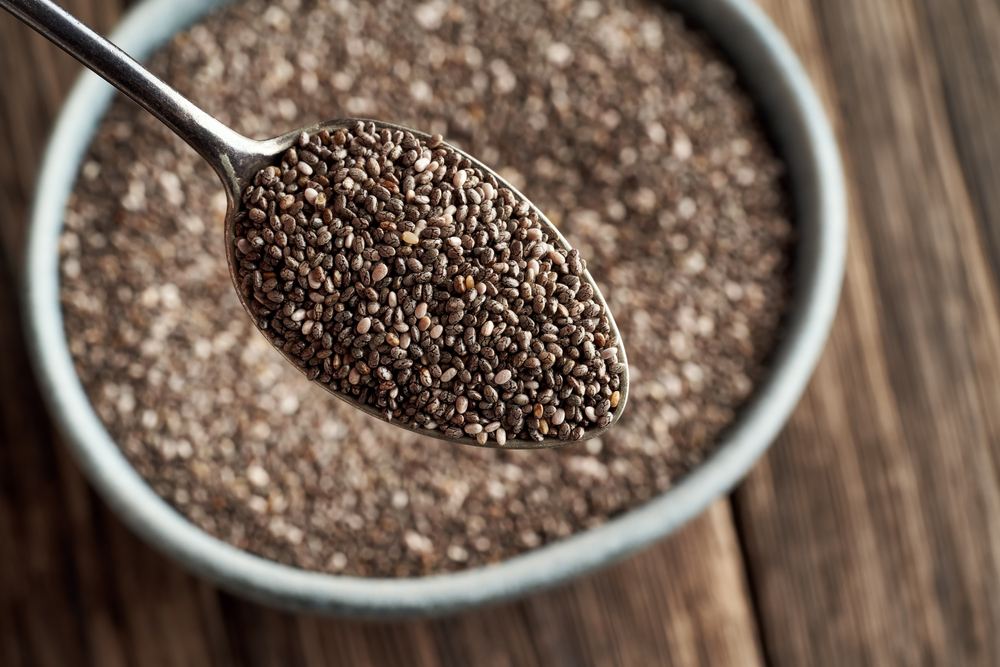 Chia seeds on a spoon above a bowl