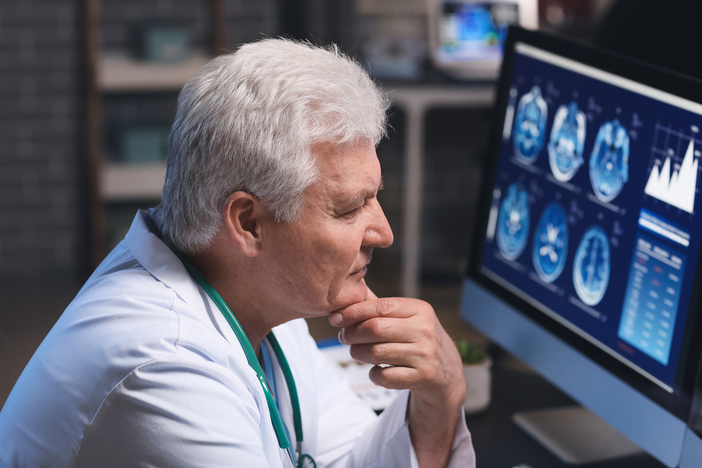 Senior neurologist with MRI scan of human head in clinic