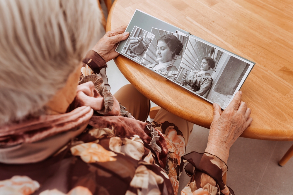 Portrait of mature woman looking at pictures in the album made many years ago. Remembering memories of family members with nostalgia and melancholy.