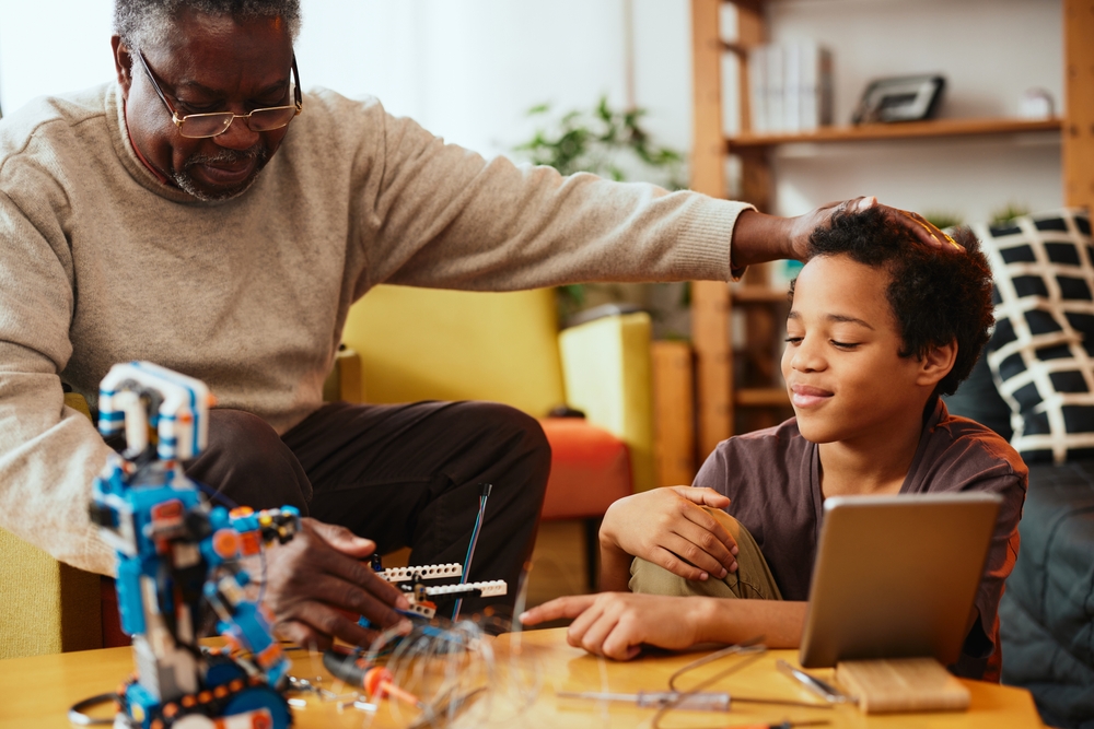 A grandad and grandson making a robot together at home. Education in robotics and electronics.