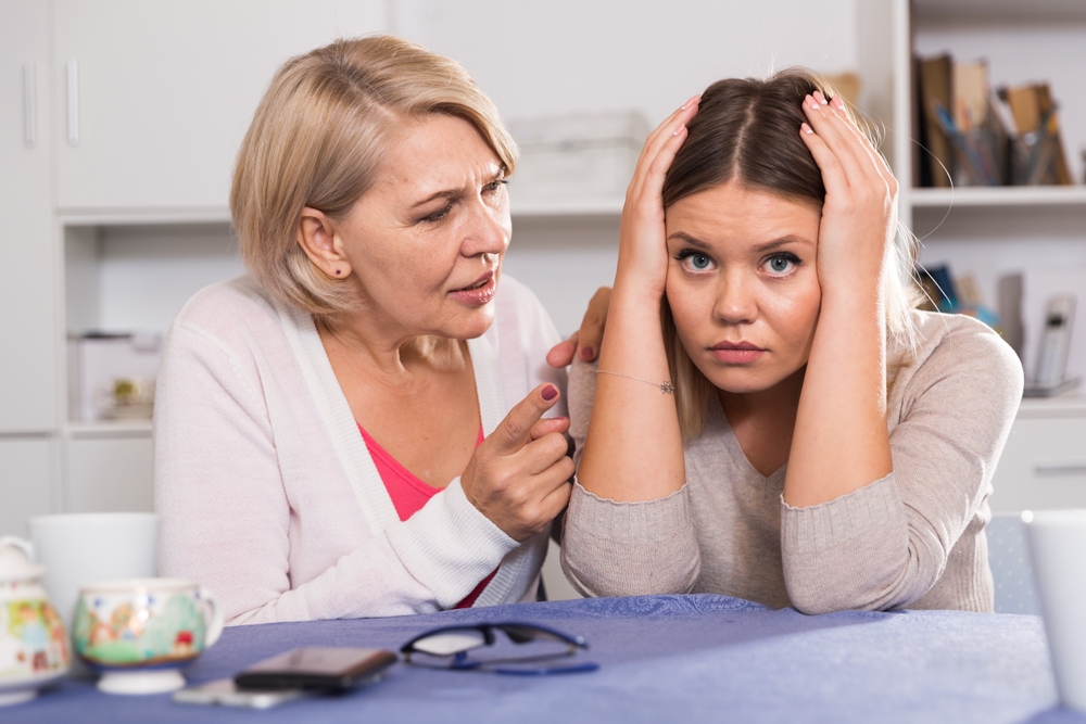 An angry mother yells at her sad older daughter