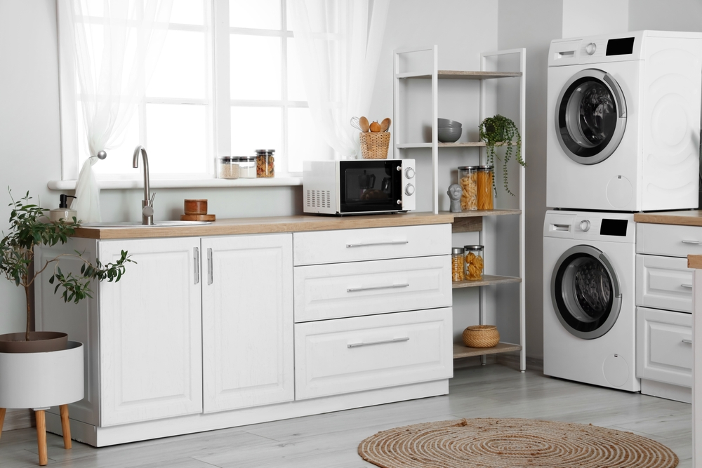 Stylish interior of kitchen with modern washing machines