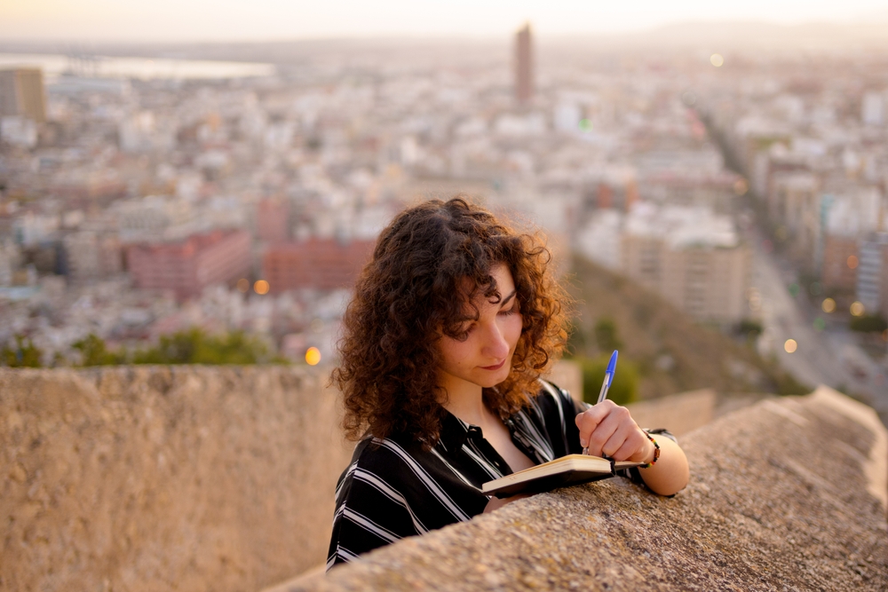 young girl in love writes in her note book thoughts outdoors