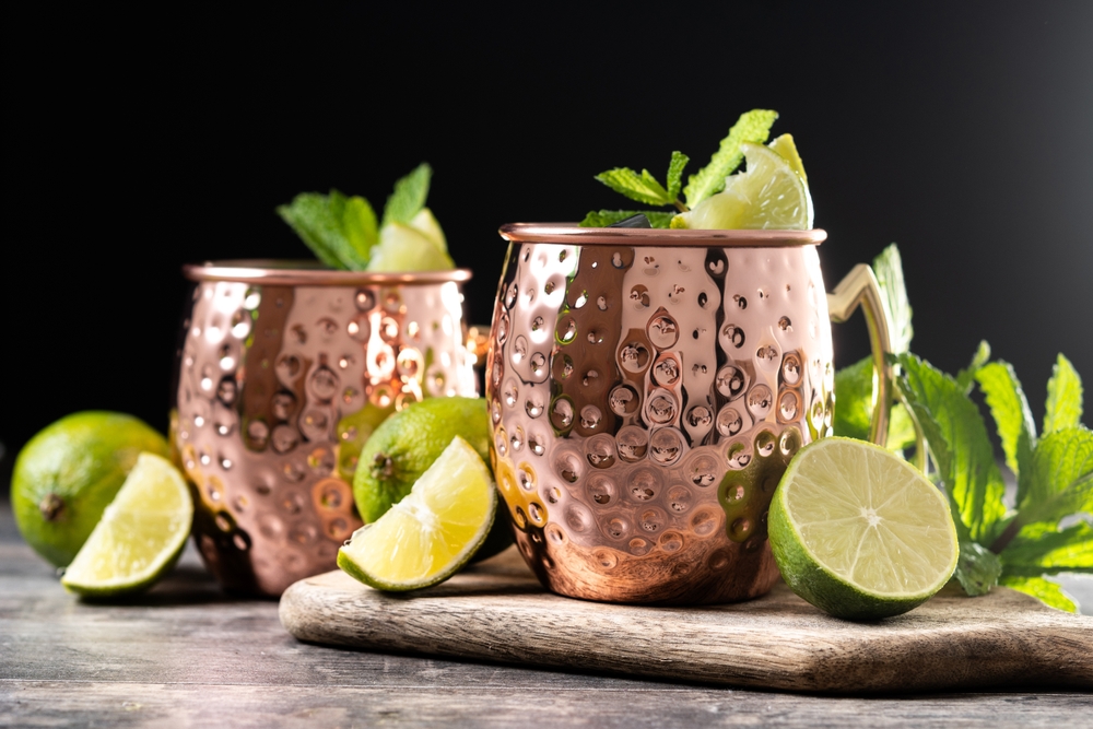 Moscow mule cocktail served with ice and lime slice on wooden table.