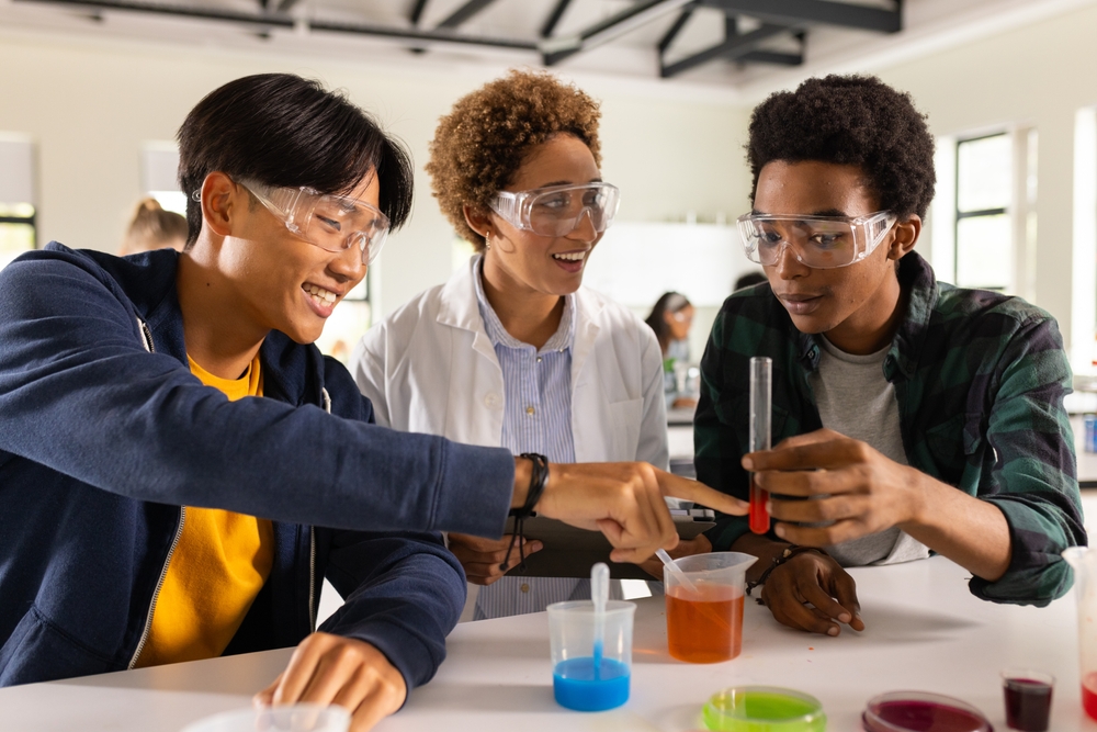 In high school, teenagers conducting science experiment with test tubes in classroom. Education, learning, chemistry, students, laboratory, collaboration