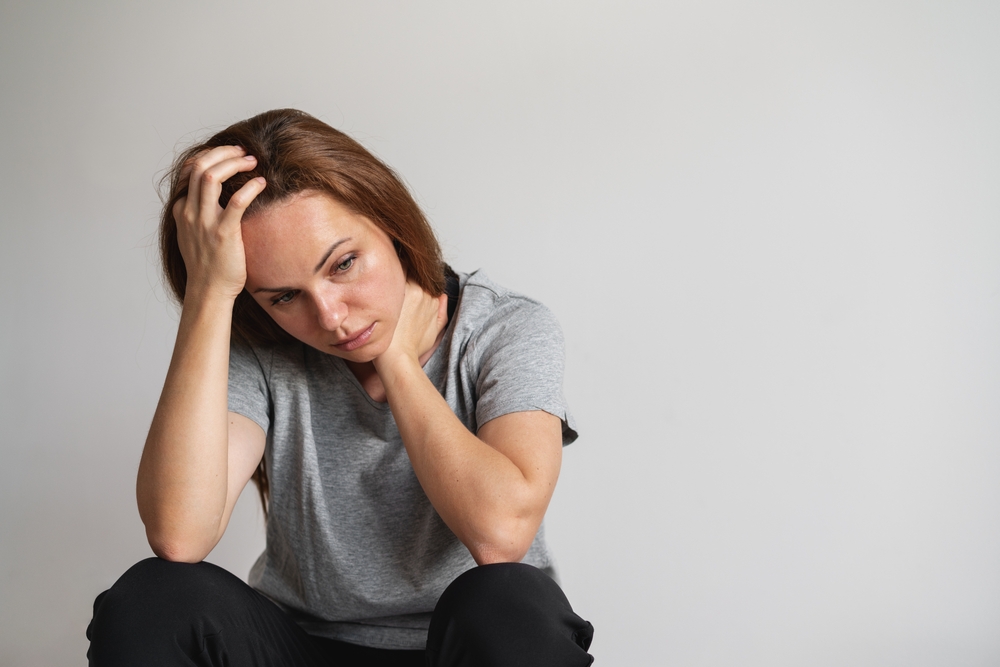 Feeling overwhelmed. Woman with head in hands. Mental illness.