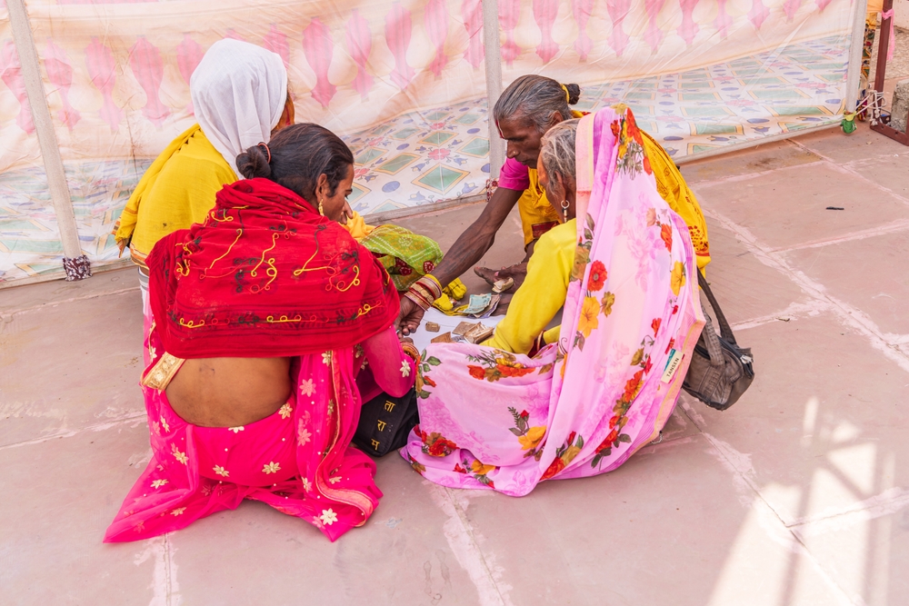 Pushkar, Rajasthan, India. November 6, 2022. Four Hijra, traditional third gender people, dividing money on the sidewalk.