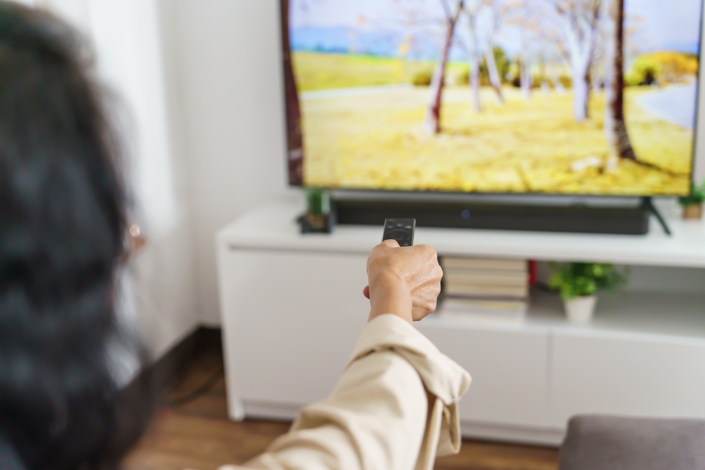 Elderly woman Watching smart TV and using remote controller Hand holding television audio remote control Middle age Asian woman movie Television series spending time at home.