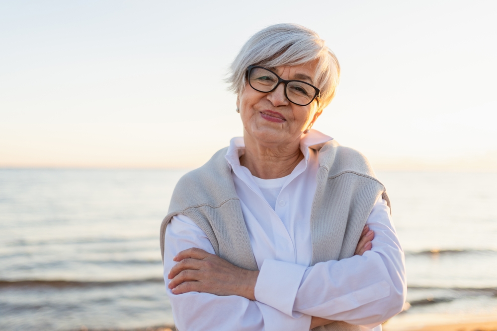 Outdoor portrait of confident stylish European middle aged senior woman. Older mature lady smiling on beach. Happy attractive senior female looking camera close up face headshot portrait. Happy people