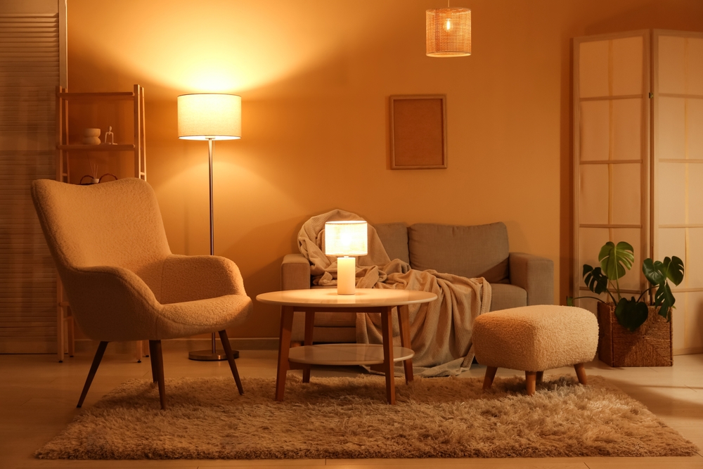 Interior of night living room with sofa, armchair, glowing lamps, folding screen and coffee table