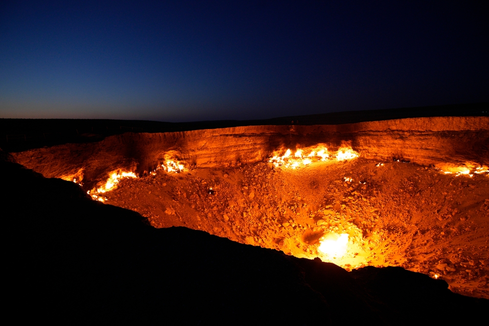 Night shot of Turkmenistan's Darvaza gas crater, ablaze since 1971 in the Karakum Desert. Known by tourists as the 'Door to Hell,' it's now under government review for closure to reduce emissions.