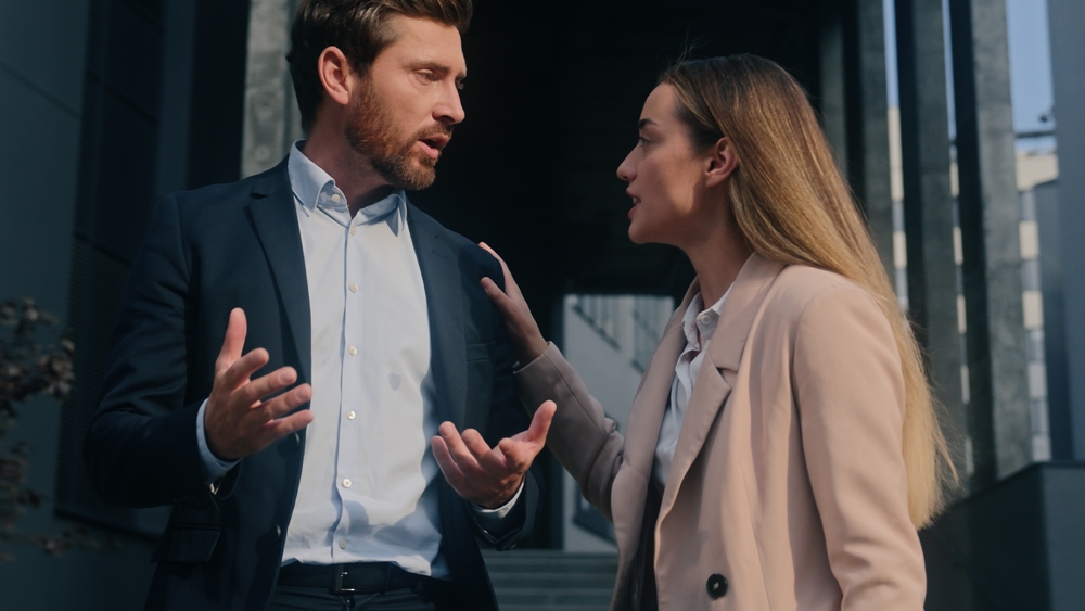 Two Caucasian business colleagues arguing talking conflict quarrel in city outdoor work problem discuss angry irritated stress man businessman guy male argument talk to businesswoman woman girl female