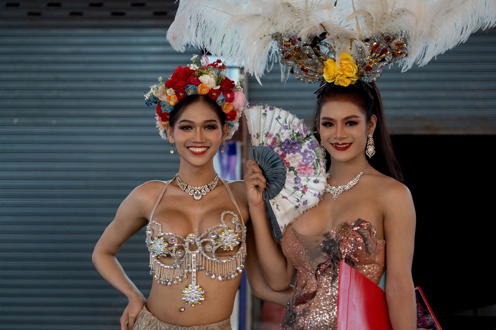 Hat Yai, Thailand - 25 Aug 2025 : Two beautiful transgender performers in ornate cabaret costumes, elaborate headdresses, and jewelry, smiling brightly.