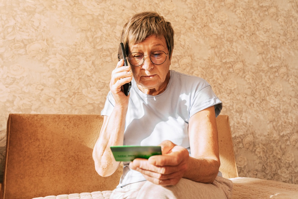 A naive elderly woman gives her bank card details to telephone scammers. Financial fraud using personal information, manipulation, criminal activity