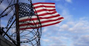 US Flag flapping in the wind with barbed wire in foreground