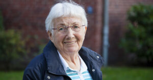 portrait of an older woman smiling, likely from a community setting focused on senior care and wellness.