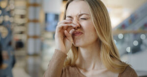 Allergy Season 2026: Is It Worse This Year and How to Find Relief woman displaying allergy symptoms rubbing her nose