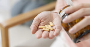 pills dispensed into man's hand from a brown medication bottle