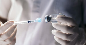 medical personnel using a syringe to extract fluid from a vile. Vaccination concept